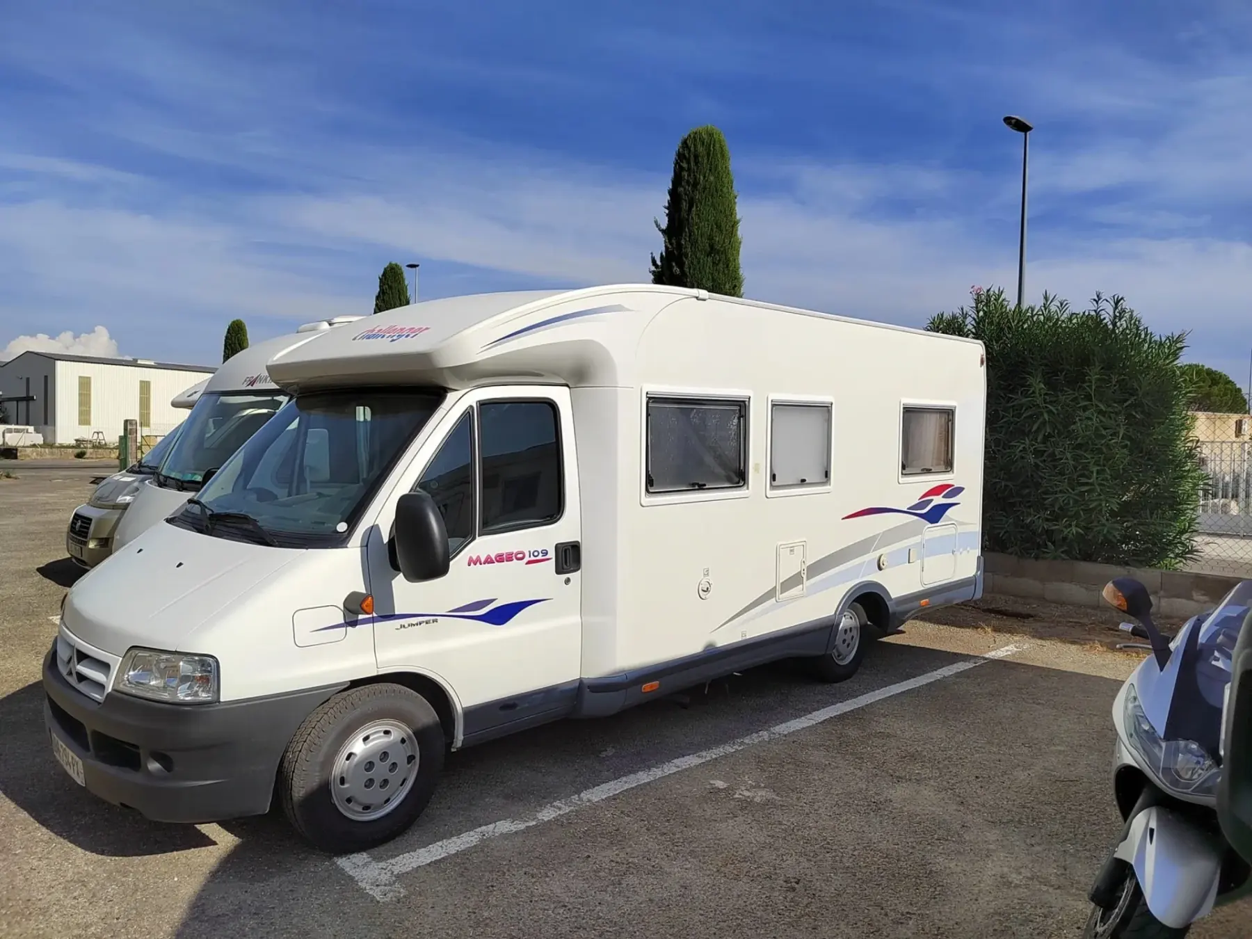 Un camping-car blanc garé devant l'atelier, sous le ciel du Vaucluse